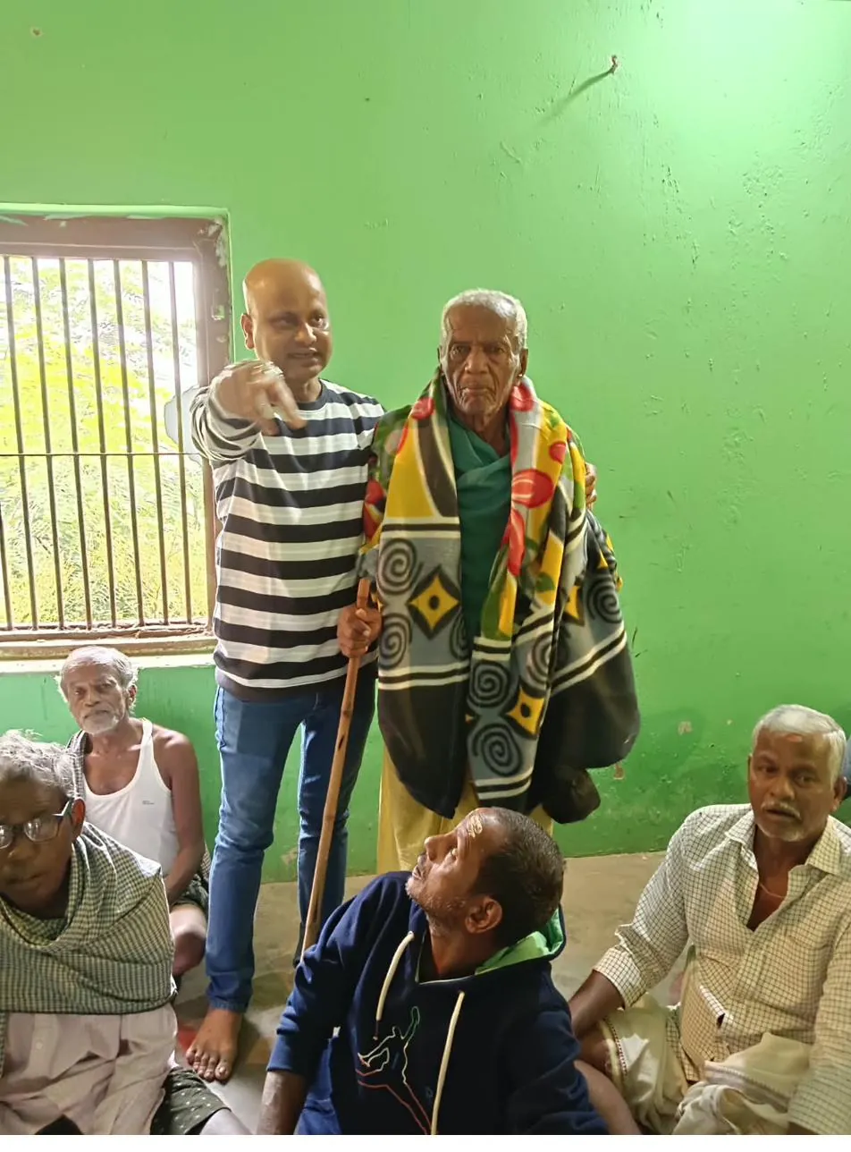 An Adarsha Odisha team member supporting an elderly community member during an outreach visit